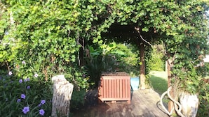 A wooden deck leading to a covered area with a bench and a planter.