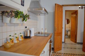 Een koelkast, een oven, een waterkoker, kookgerei, borden en bestek