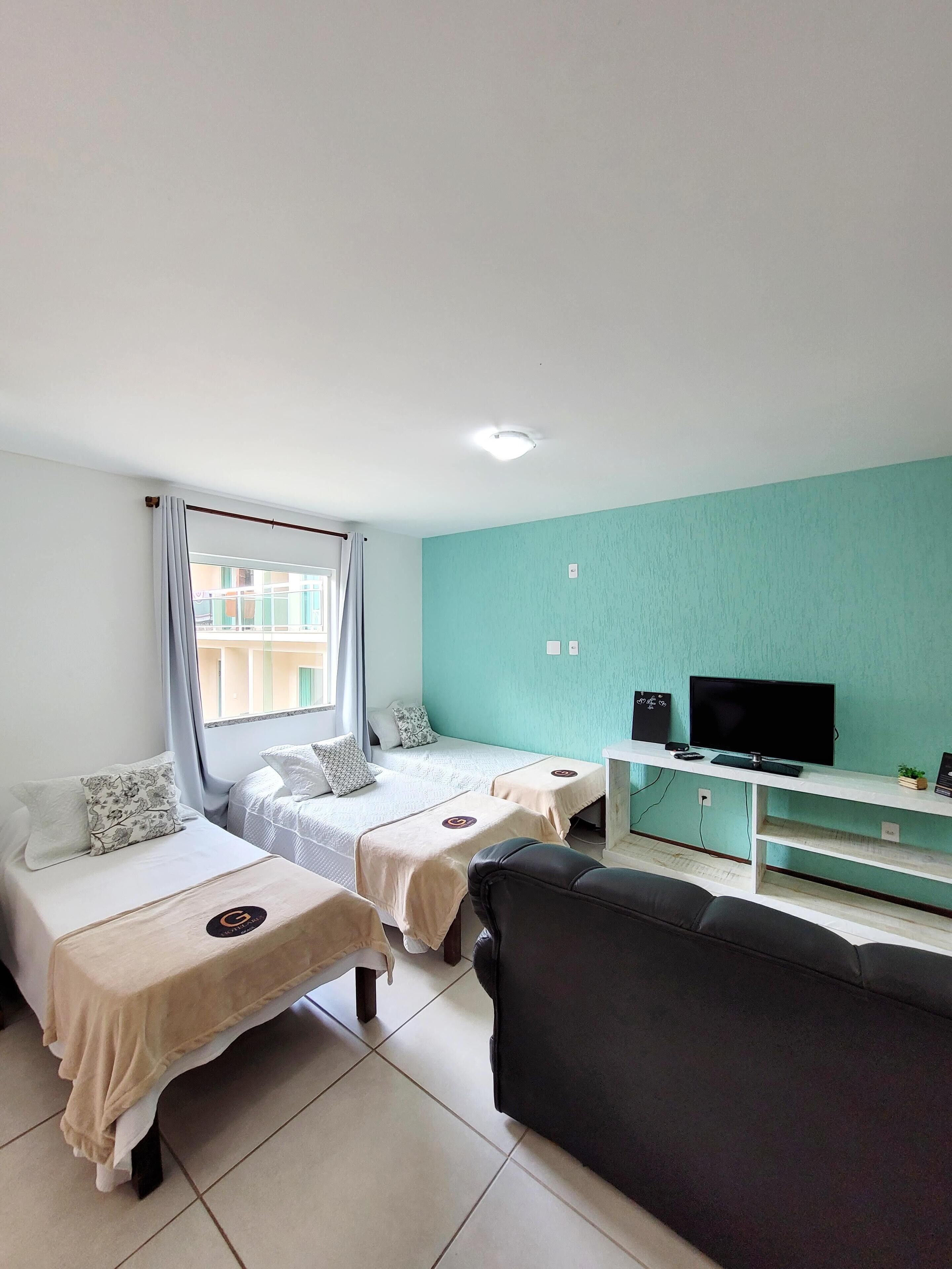 A room with two single beds, a sofa, a TV, and a small table.