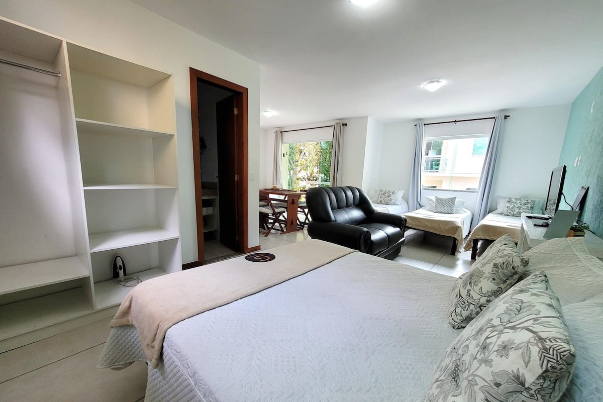 Un dormitorio moderno con una cama grande, un escritorio, una silla y un armario.