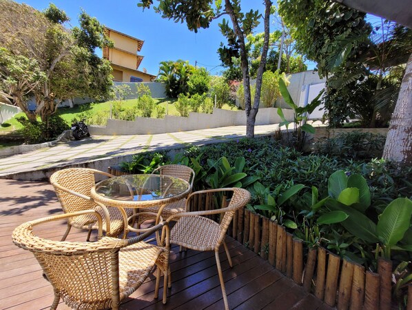 A patio with wicker furniture and a view of a building in the background. - Solar João Fernandes (Búzios)