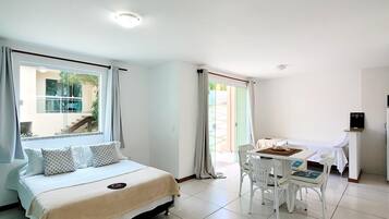 Quarto de hotel com cama, mesa de jantar e cadeiras, e vista para o exterior.