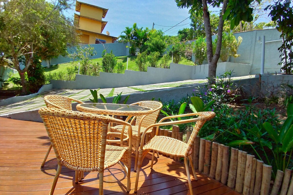 Una terraza de madera con mobiliario de mimbre y vistas a una zona residencial.