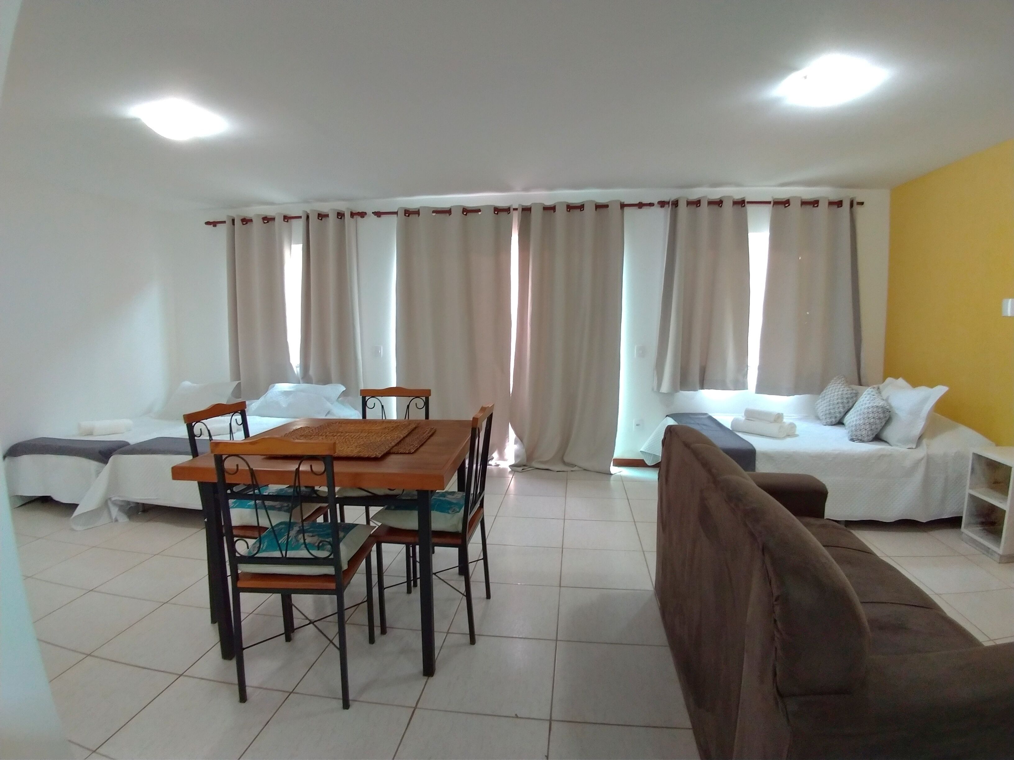 A hotel room with a dining table, chairs, a sofa, and two beds.