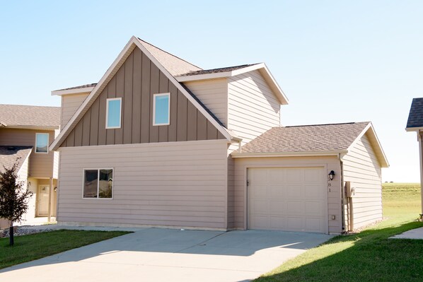 A two-story house with a garage, a small front yard, and a clear sky.