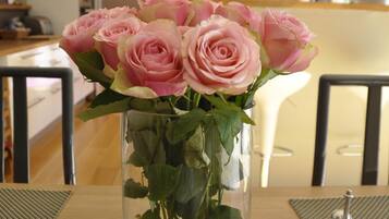 Un vase en verre transparent contenant des roses roses, posé sur une table en bois.