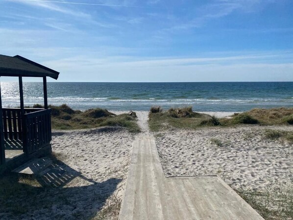 A beach pathway leading to the ocean with a wooden structure on the left. - Flygarevägen (Hollviken)