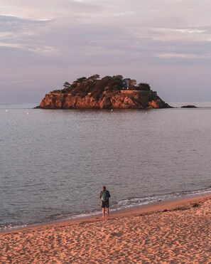 A beach with a person standing on the sand, a rocky island in the background, and calm water. - ⭐ "Presqu'île," cozy charm just 200 meters from the sea ⭐ (Cancale)