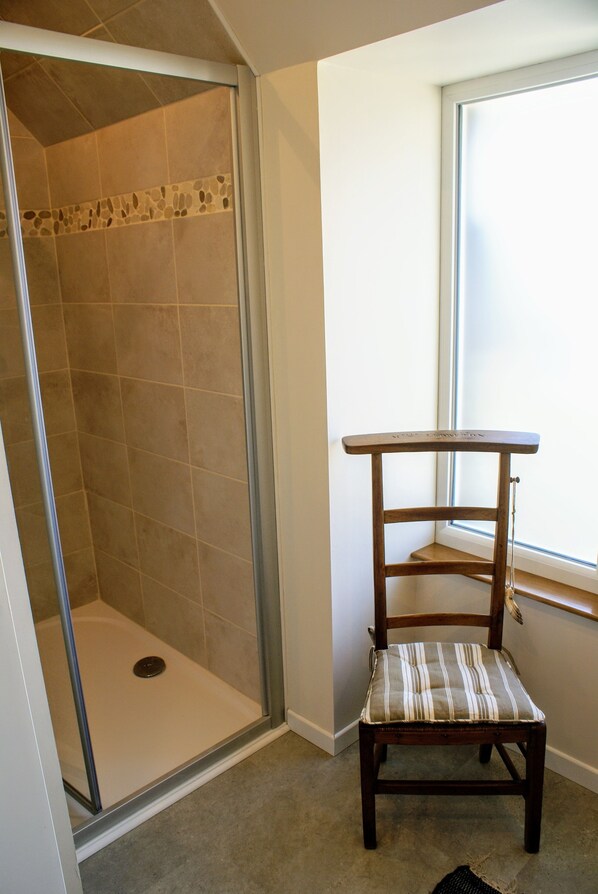 A shower with a glass door, a wooden chair with a striped cushion, and a window with a view of the outside. - ⭐ "Presqu'île," cozy charm just 200 meters from the sea ⭐ (Cancale)