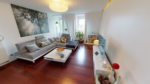 A modern living room with a sofa, coffee table, and a painting on the wall.