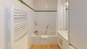 A bathroom with a bathtub, a shower, a towel rack, and a sink.