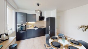 A modern kitchen with dark cabinetry, a built-in oven, a microwave, and a refrigerator.