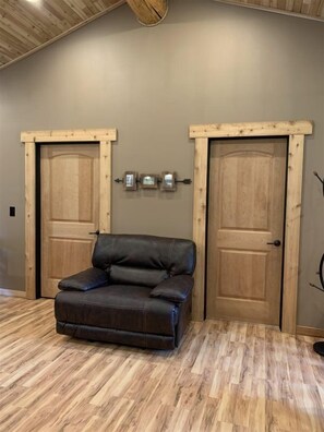 A room with a brown leather sofa, two wooden doors, and a wooden ceiling. - Aspen Cabin (Packwood)