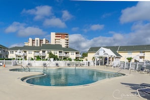 Relax by the resort pool surrounded by lounge chairs and modern architecture.