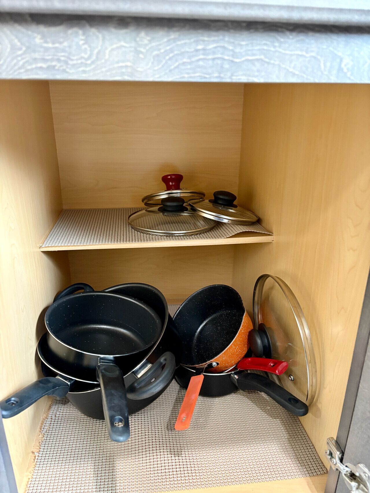 A kitchen cabinet with pots and pans stored on shelves.