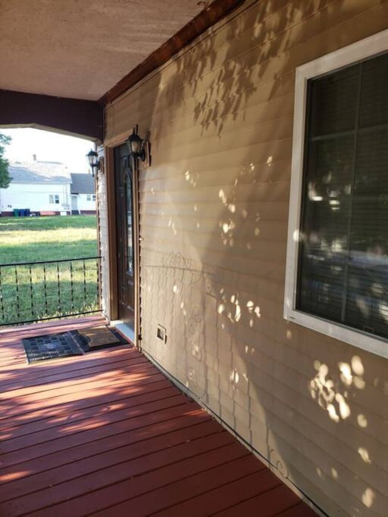 A wooden porch with a metal railing, a single door, and a window.