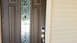 Une porte d’entrée marron avec un panneau de verre et un carillon.