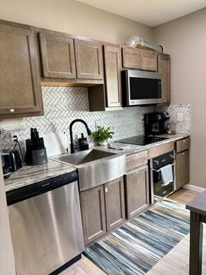 A modern kitchen with stainless steel appliances, a herringbone tile backsplash, and wooden cabinets. - Nice house with king bed 25min to Niagara falls (Buffalo)