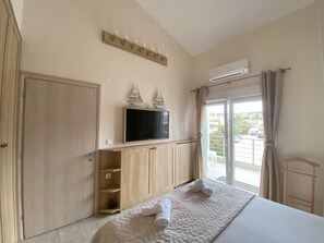 Ein Hotelzimmer mit Bett, Fernseher, Holzschrank, Balkon mit Blick und Klimaanlage.