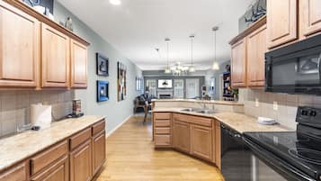 A kitchen with wooden cabinets, a black stove, and a central island with a sink.