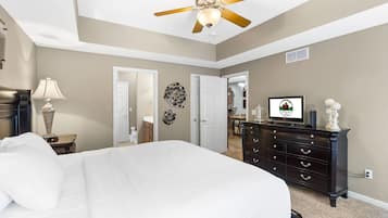 A bedroom with a bed, a dresser, a ceiling fan, and a television.