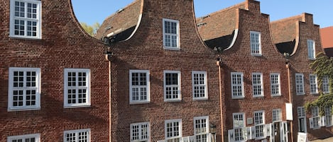 A row of red brick buildings with white window frames and green doors.
