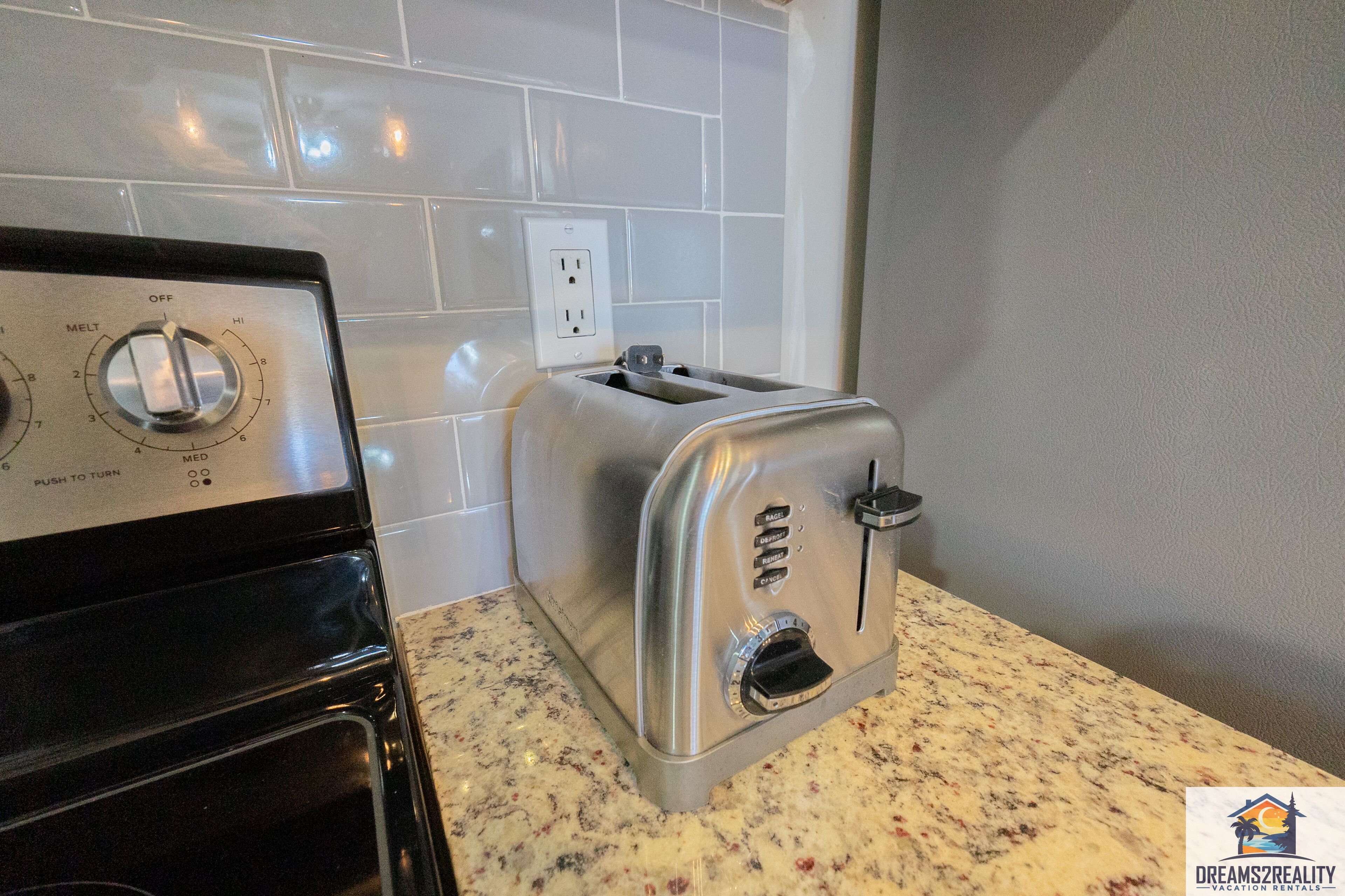 A kitchen with a stove, a toaster, and a tiled backsplash.