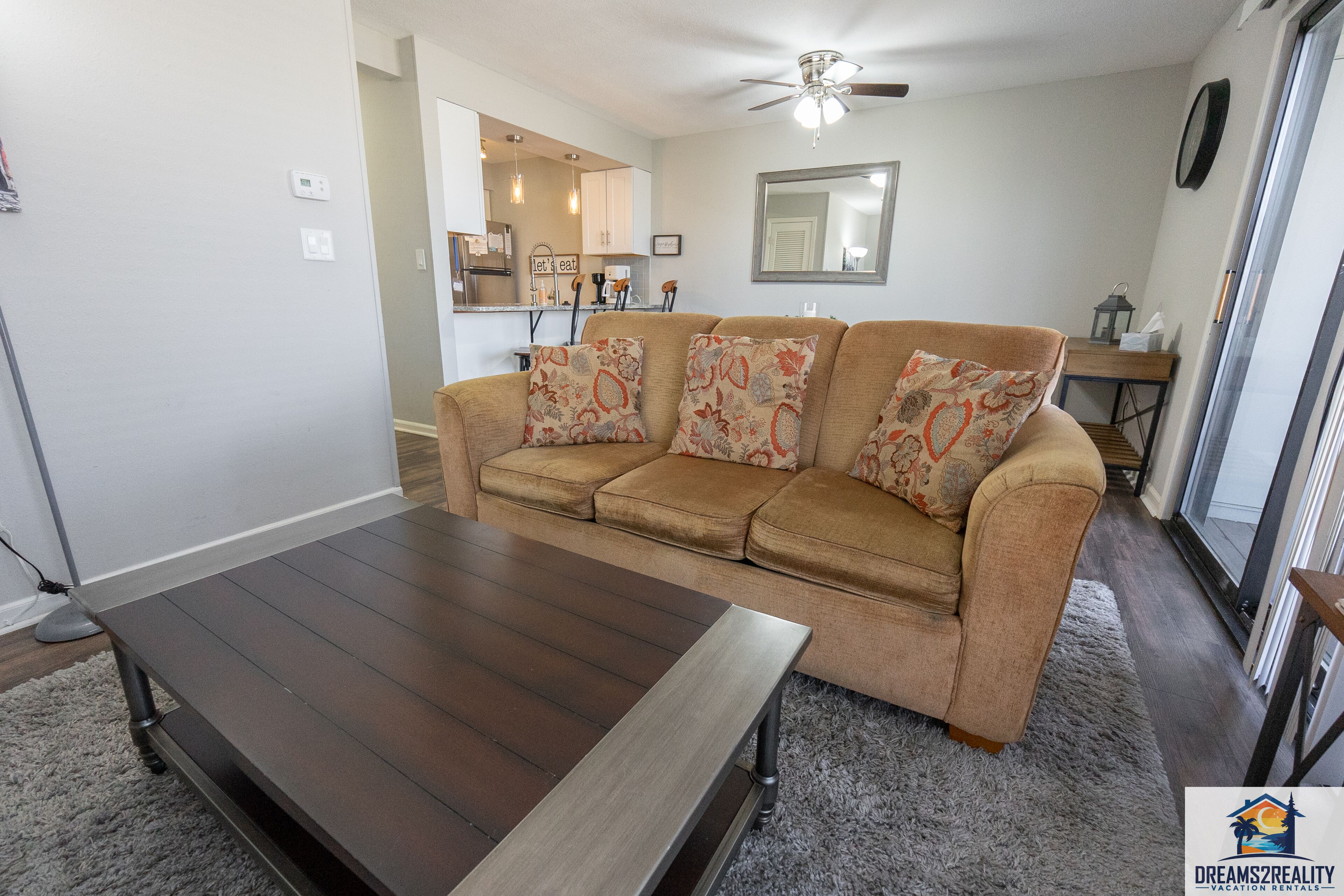 A living room with a sofa, a coffee table, and a ceiling fan.