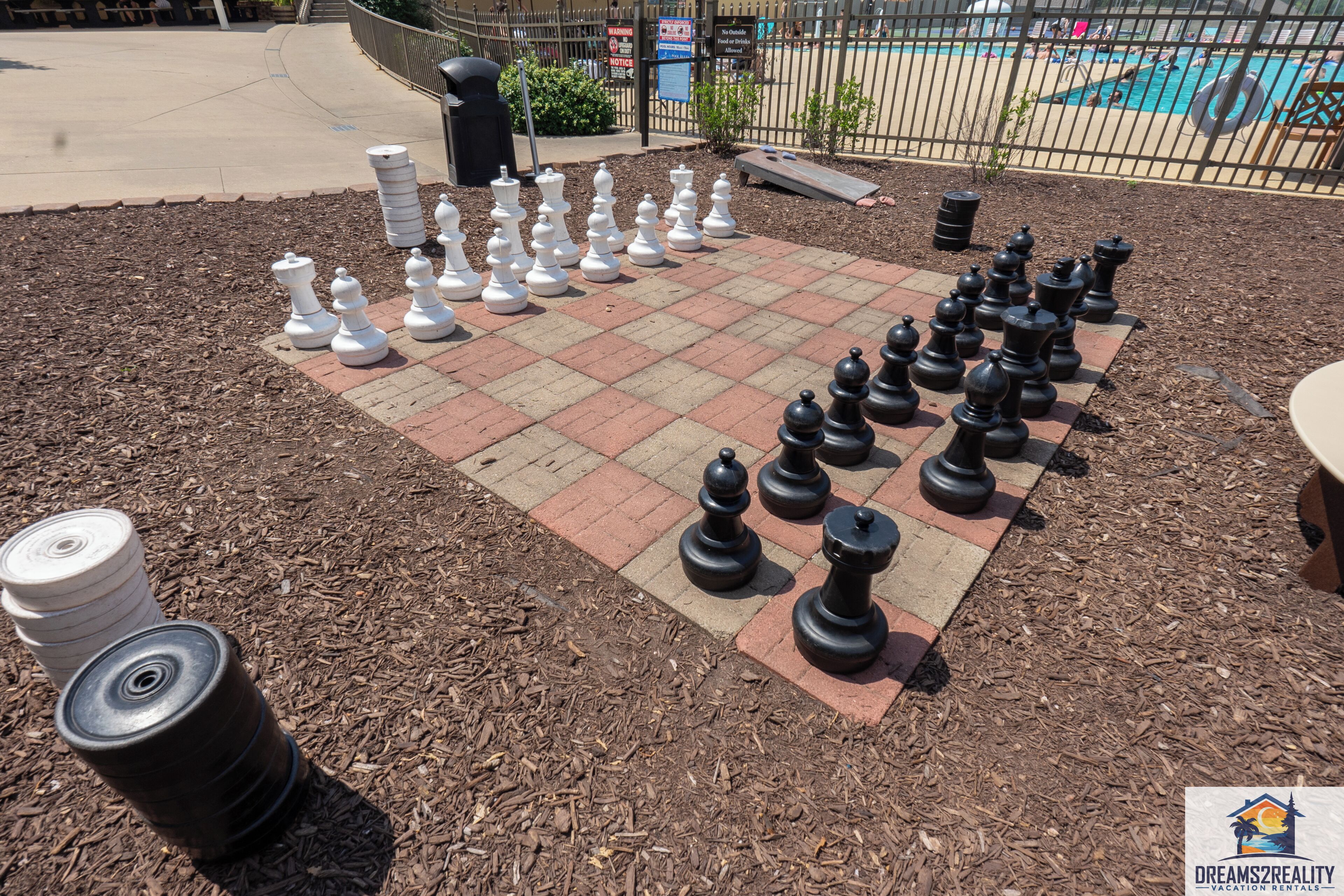 A chessboard set up outdoors with a pool in the background.
