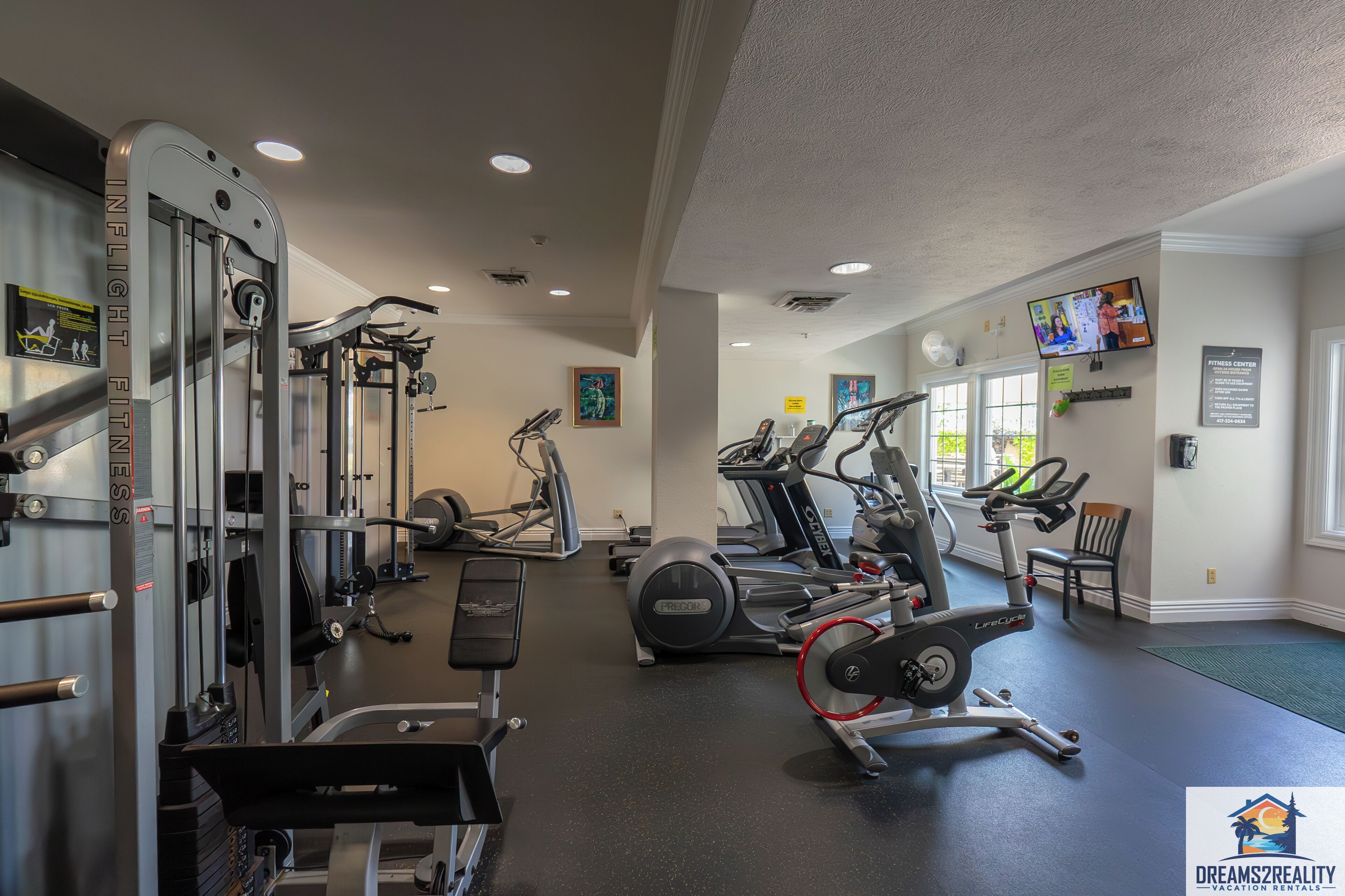 Une salle de sport équipée de divers appareils d’exercice, notamment des tapis de course, des vélos elliptiques et des appareils de musculation.