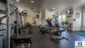 Une salle de sport équipée de divers appareils d’exercice, notamment des tapis de course, des vélos elliptiques et des appareils de musculation.