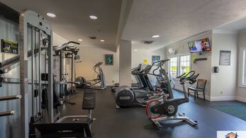 Une salle de sport équipée de divers appareils d’exercice, notamment des tapis de course, des vélos elliptiques et des appareils de musculation.
