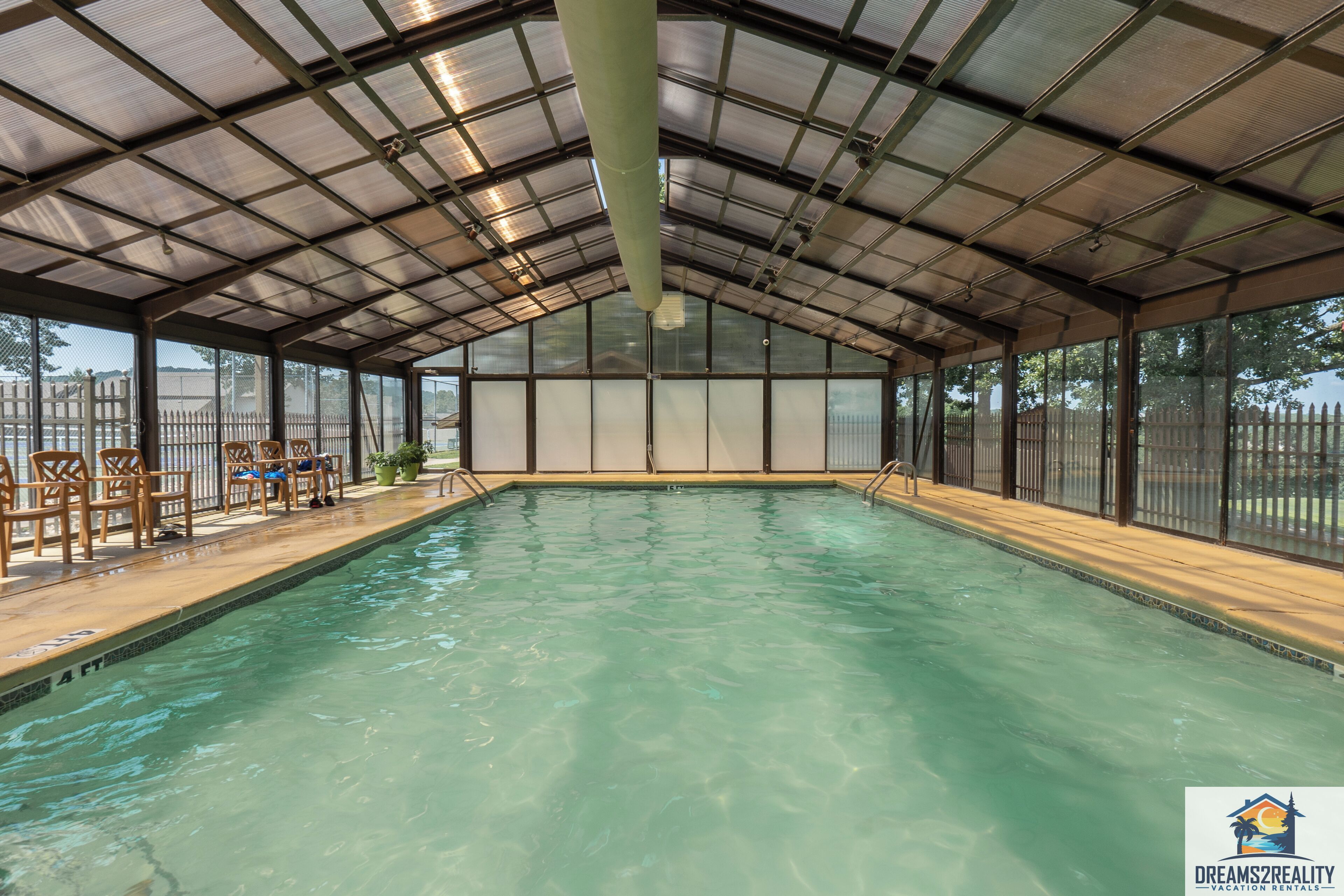 Une piscine intérieure dotée d’un toit couvert, d’une terrasse en bois et de chaises.
