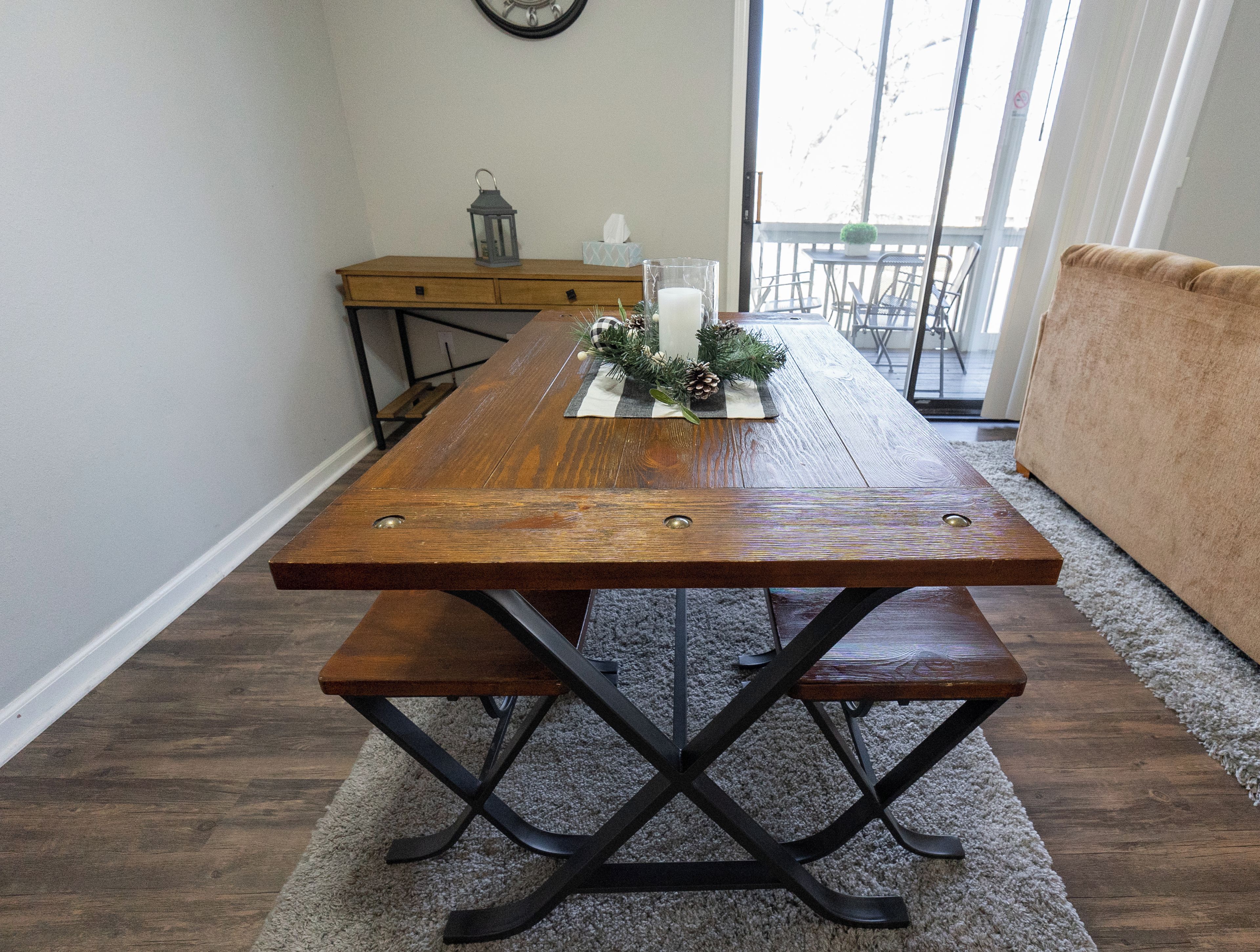 Une table à manger avec des bancs, une horloge au mur et un balcon avec vue.