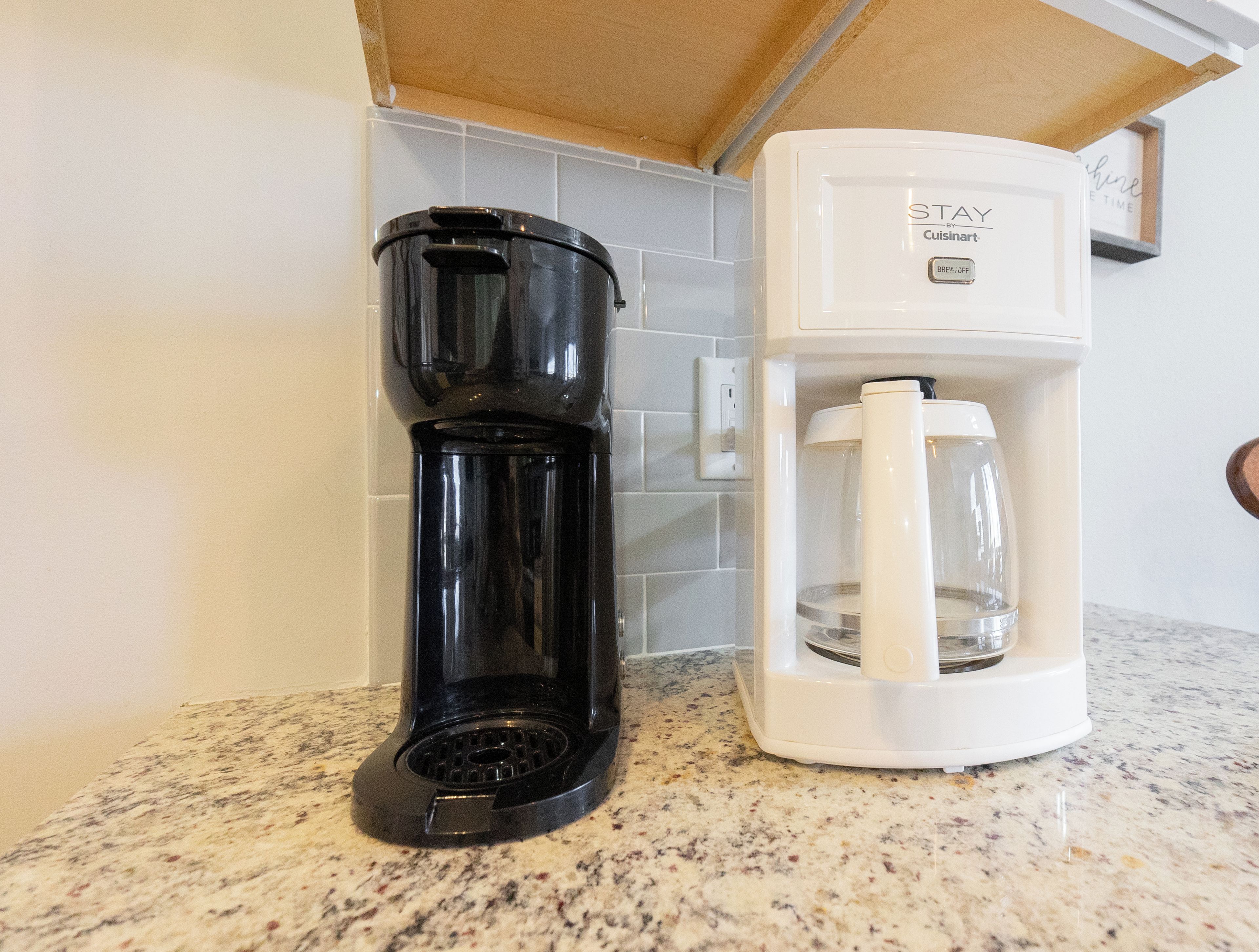 Een keuken met een koffiezetapparaat en een waterdispenser op een granieten aanrecht.