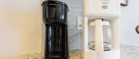 Een keuken met een koffiezetapparaat en een waterdispenser op een granieten aanrecht.