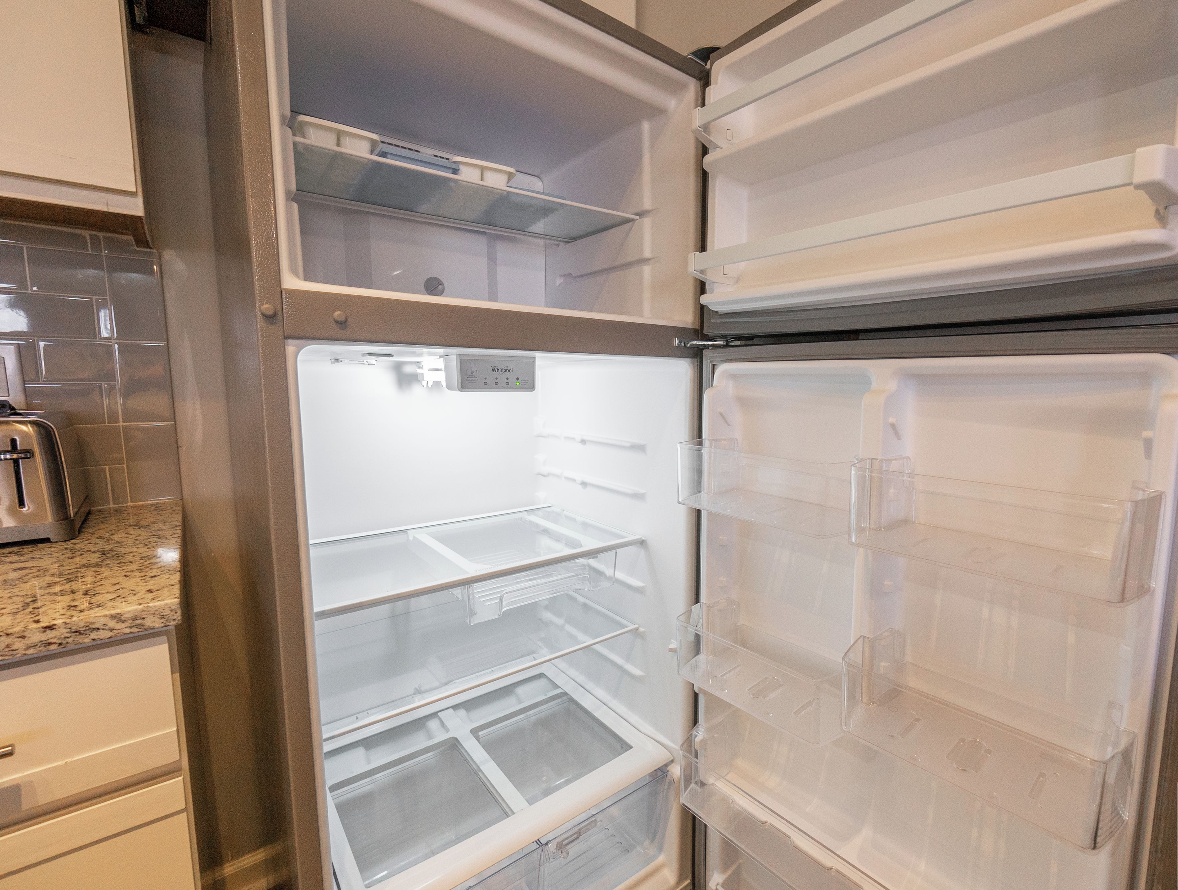 A kitchen with a stainless steel refrigerator, a toaster, and a microwave.