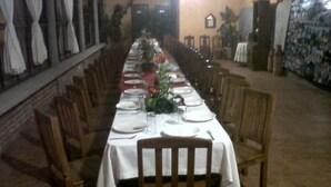 A long dining table set for a meal with chairs on both sides, in a room with tiled flooring and wooden furniture. - Villas Tonantzintla (San Andrés Cholula)