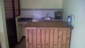 A small kitchen with a wooden counter, a sink, and a water dispenser. - Villas Tonantzintla (San Andrés Cholula)