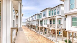A row of seaside cottages with wooden decks and balconies, connected by a shared walkway.