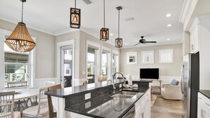 A modern kitchen with a large island, stainless steel appliances, and pendant lighting.
