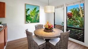 Een eetgedeelte met een ronde tafel, rieten stoelen en een hanglamp.