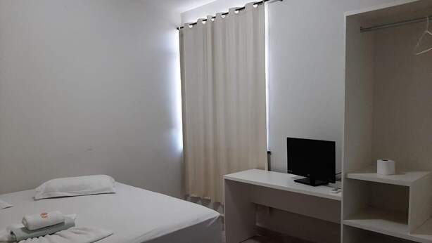A hotel room with a bed, a desk with a computer, a wardrobe, and a bathroom. - Hotel Trevo (Boa Vista)