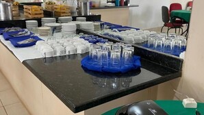 A buffet setup with plates, glasses, and utensils on a counter. - Hotel Trevo (Boa Vista)