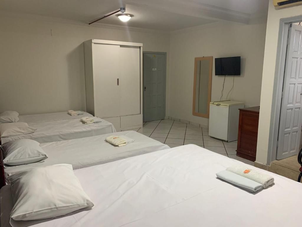 A hotel room with two beds, a wardrobe, a television, and a desk.