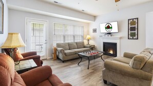 A living room with a sofa, armchairs, a coffee table, a fireplace, and a television. - Gated 5BR Retreat • Private Patio • Sleeps 12 • Pool • Near Shows, Golf & Dining (Branson)