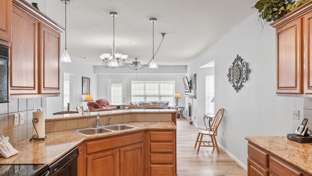 A spacious kitchen with wooden cabinets, a large island, and a chandelier. - Gated 5BR Retreat • Private Patio • Sleeps 12 • Pool • Near Shows, Golf & Dining (Branson)