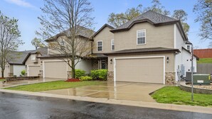 A two-story residential house with a garage, a well-maintained lawn, and a driveway. - Gated 5BR Retreat • Private Patio • Sleeps 12 • Pool • Near Shows, Golf & Dining (Branson)
