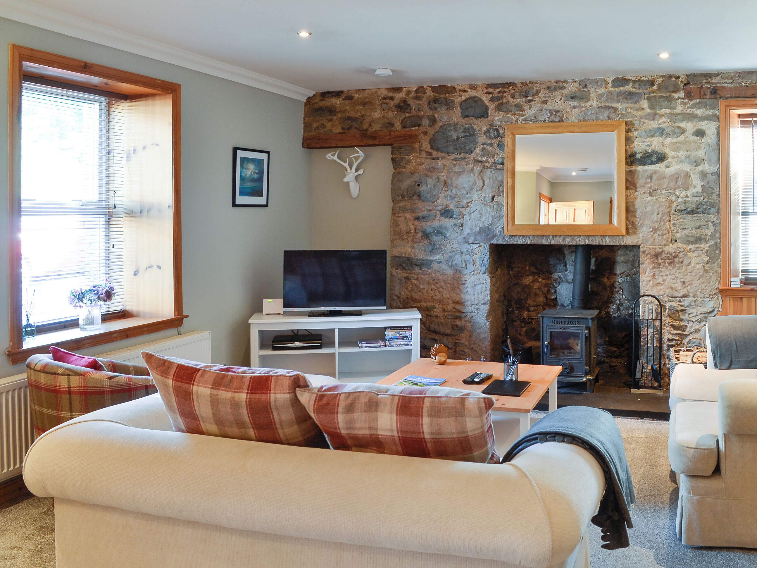 A cozy living room with a stone wall, a fireplace, a television, and a comfortable sofa.