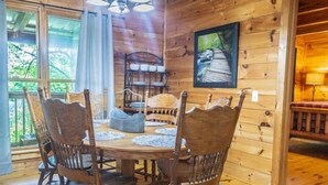 Ein Essbereich aus Holz mit einem runden Tisch, vier Stühlen und einer Pendelleuchte.